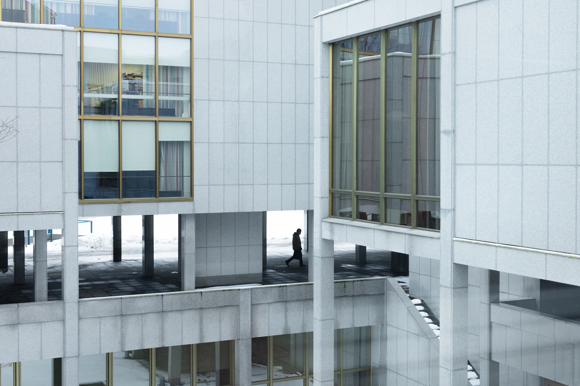 Illustration: a man walking in the courtyard of a gray building.