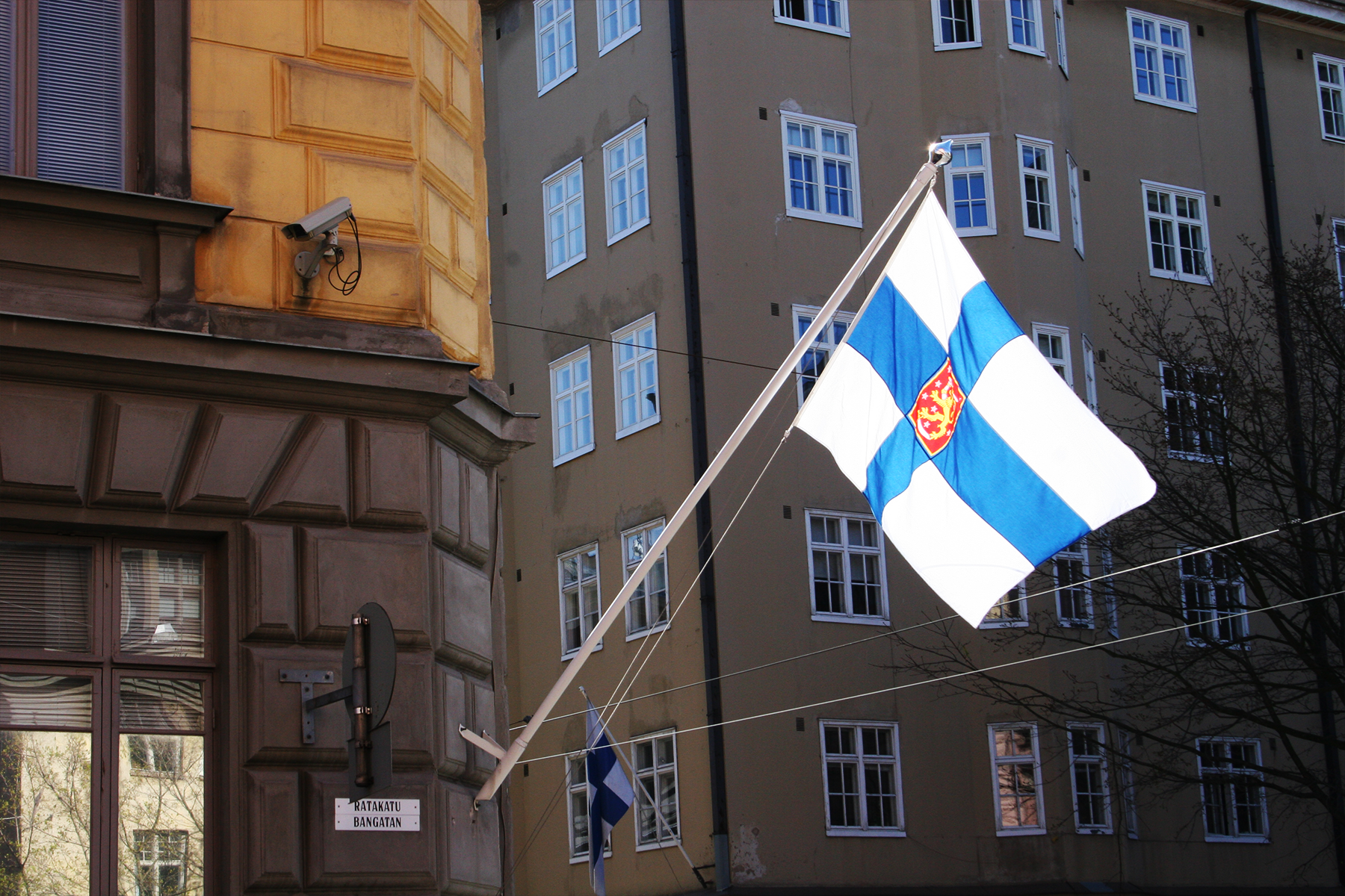 Kuvituskuva - Suojelupoliisin rakennuksen kulma Helsingissä ja Suomen lippu.